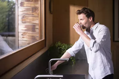 Man drinking a glass of water from the tap - municipal drinking water treatment
